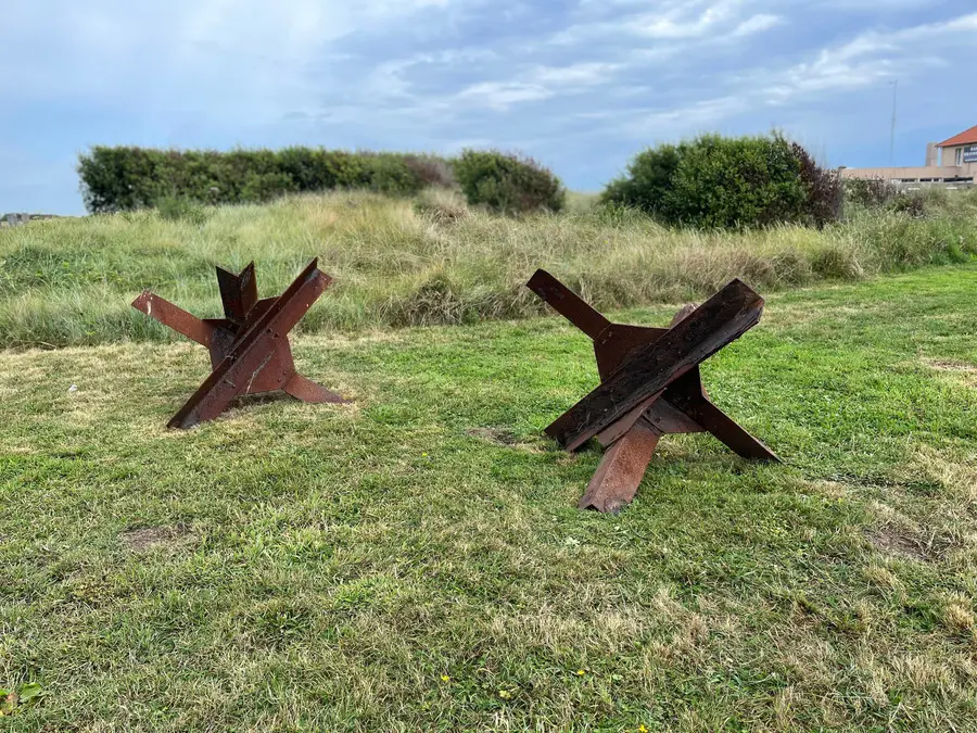 Rusted steel beach obstacles displayed on the sand at Utah Beach.