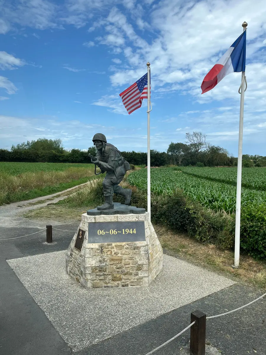 A bronze statue of Major Richard Winters in combat dress, striding forward on a stone plinth.
