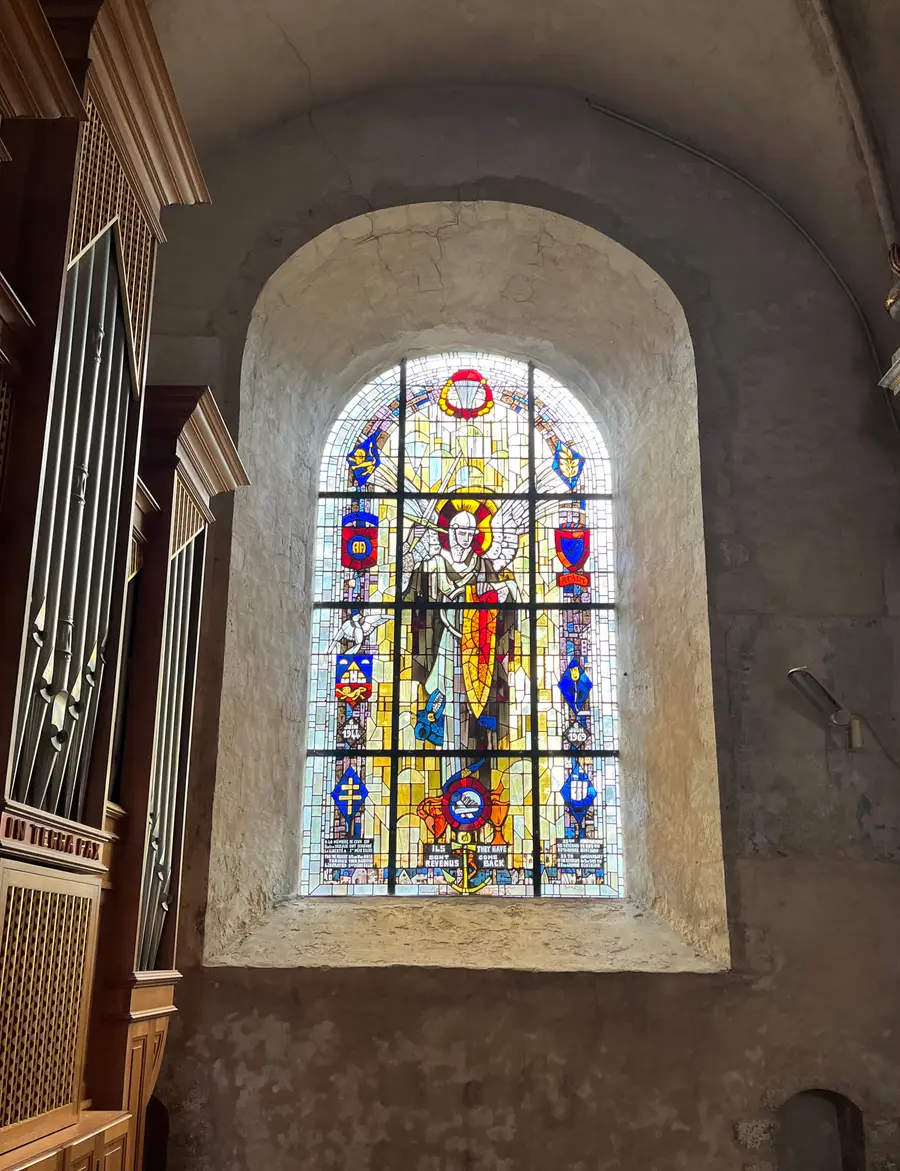 Stained glass window of the Virgin Mary flanked by descending paratroopers.
